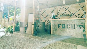 An outdoor seating area with a concrete counter labeled "FOCU" and a geometric ceiling design. - Focus Rooms (El Nido)