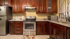 Una cocina con armarios de madera, electrodomésticos de acero inoxidable, encimeras de granito y un microondas.