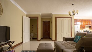 Una sala de estar con televisor, sofá, reposapiés y alfombra.