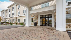 A multi-story building with a stone facade and a brick-paved entrance area. - Comfort Inn Brewster (Brewster)