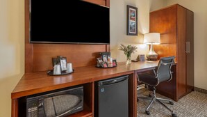 A hotel room with a wooden desk, a television, a coffee maker, a lamp, a chair, and a wardrobe. - Comfort Inn Brewster (Brewster)
