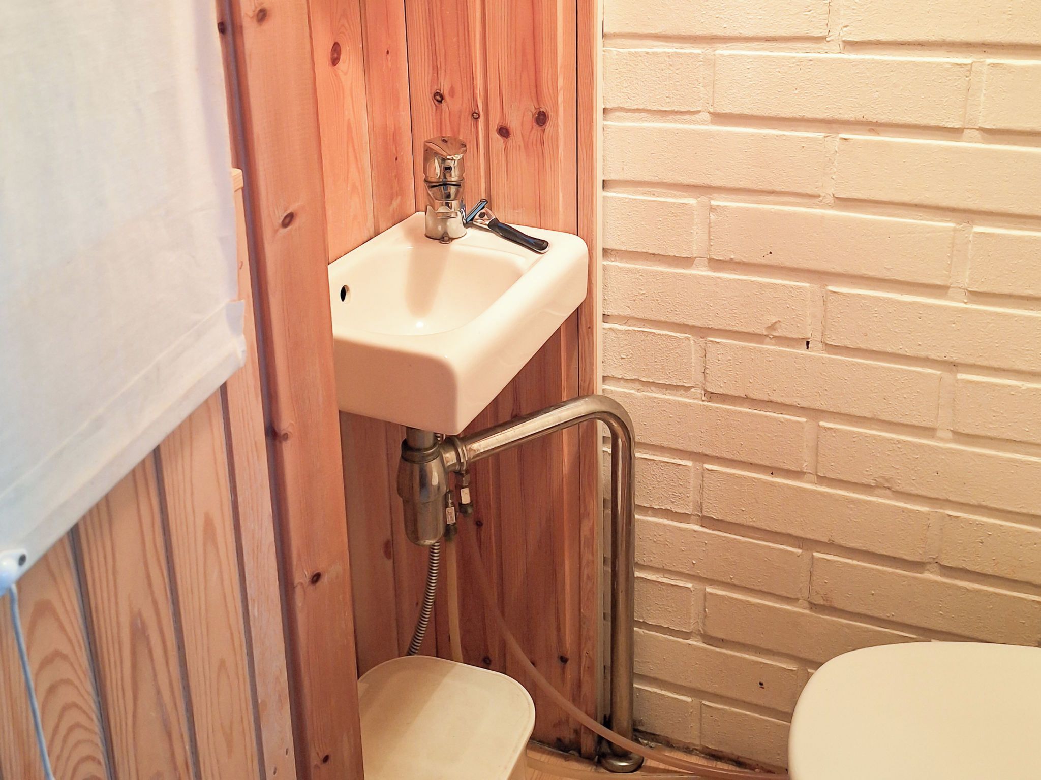 Un baño pequeño con pared de madera, un lavabo blanco y un inodoro.