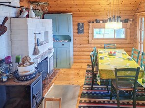A cozy cabin interior with a dining table, chairs, a fireplace, and a window.