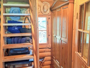 A wooden interior with a built-in shelf unit holding various items, a wooden wardrobe, and a window with a view. - Honkaranta by Interhome (Karstula)