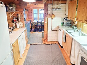 Una cucina compatta con mobili in legno, lavastoviglie integrata e un'area pranzo con tavolo e sedie.