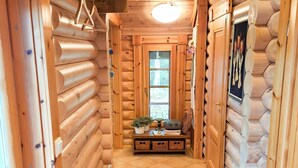 A log cabin interior with a tiled floor, wooden walls, a small table with a radio, and a window with a view of greenery. - Honkaranta by Interhome (Karstula)