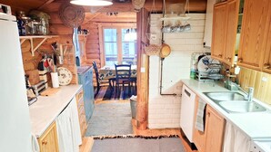 A cozy kitchen with wooden cabinets, a dining area, and a view of a forest through the window. - Honkaranta by Interhome (Karstula)
