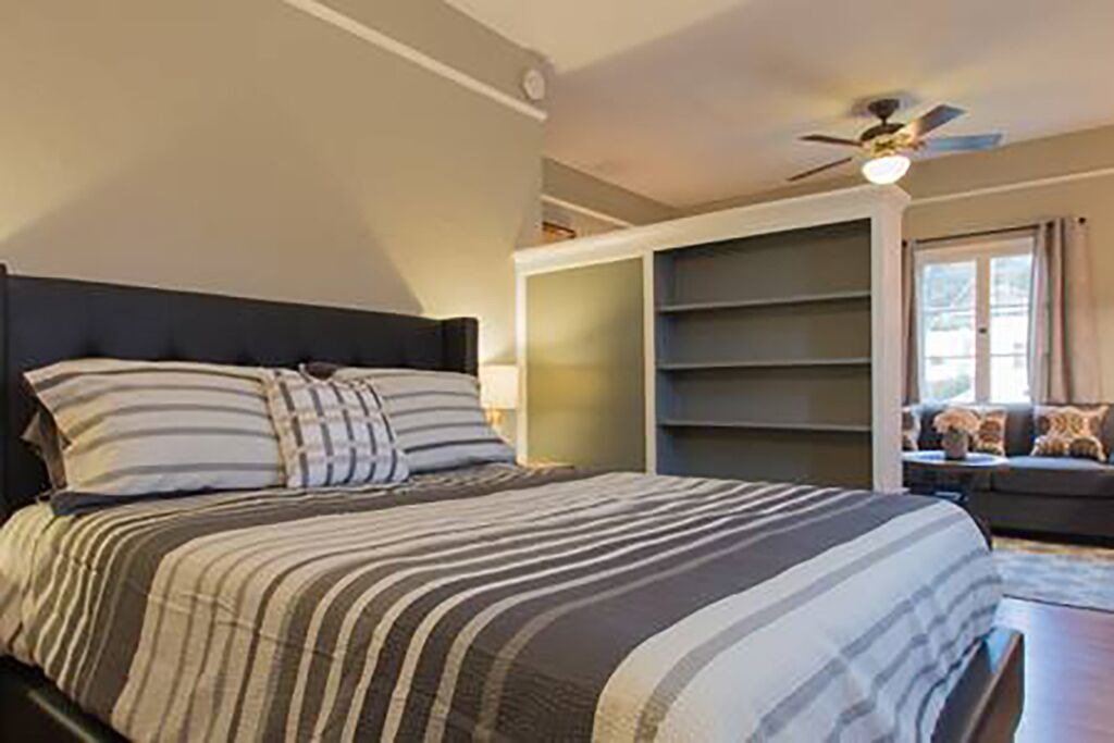 Un dormitorio con cama, ventilador de techo y estantes empotrados.