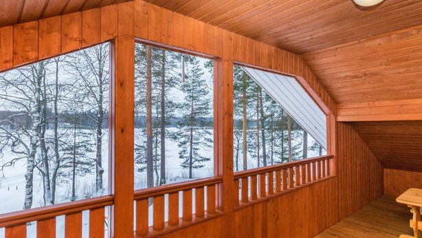 Une cabane dotée de grandes fenêtres, de murs en bois et d’un plafond en bois.
