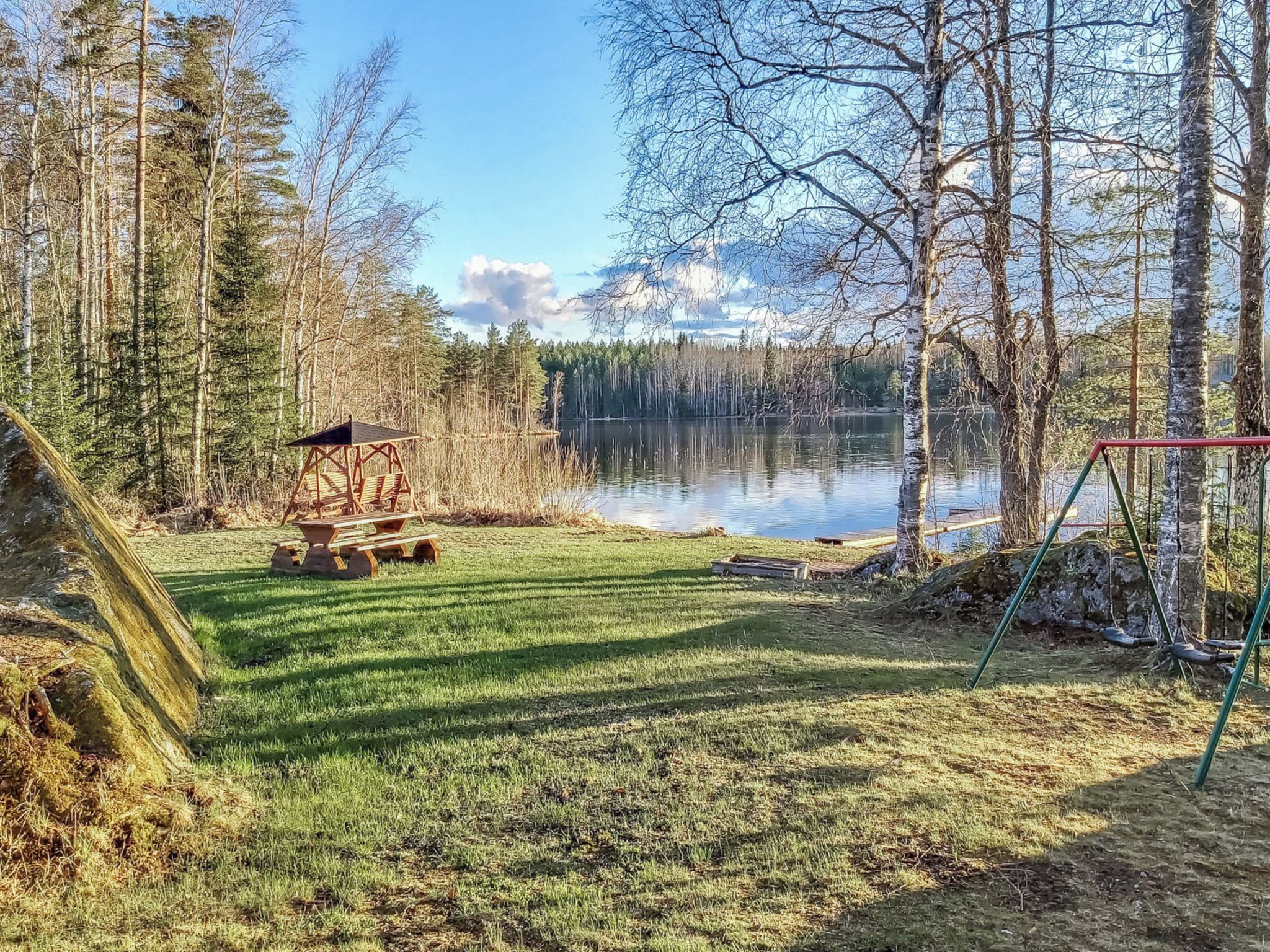 Una propiedad frente al lago con una mesa de picnic, un columpio y una estructura de madera para observar el paisaje.