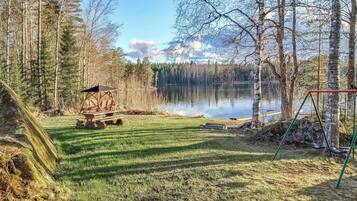Una propiedad frente al lago con una mesa de picnic, un columpio y una estructura de madera para observar el paisaje.