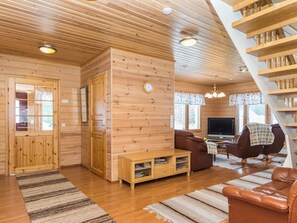 Un interior de madera con un sofá, televisor y una escalera.