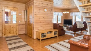 Un intérieur en bois comprenant un escalier, un canapé, un téléviseur et un meuble en bois.