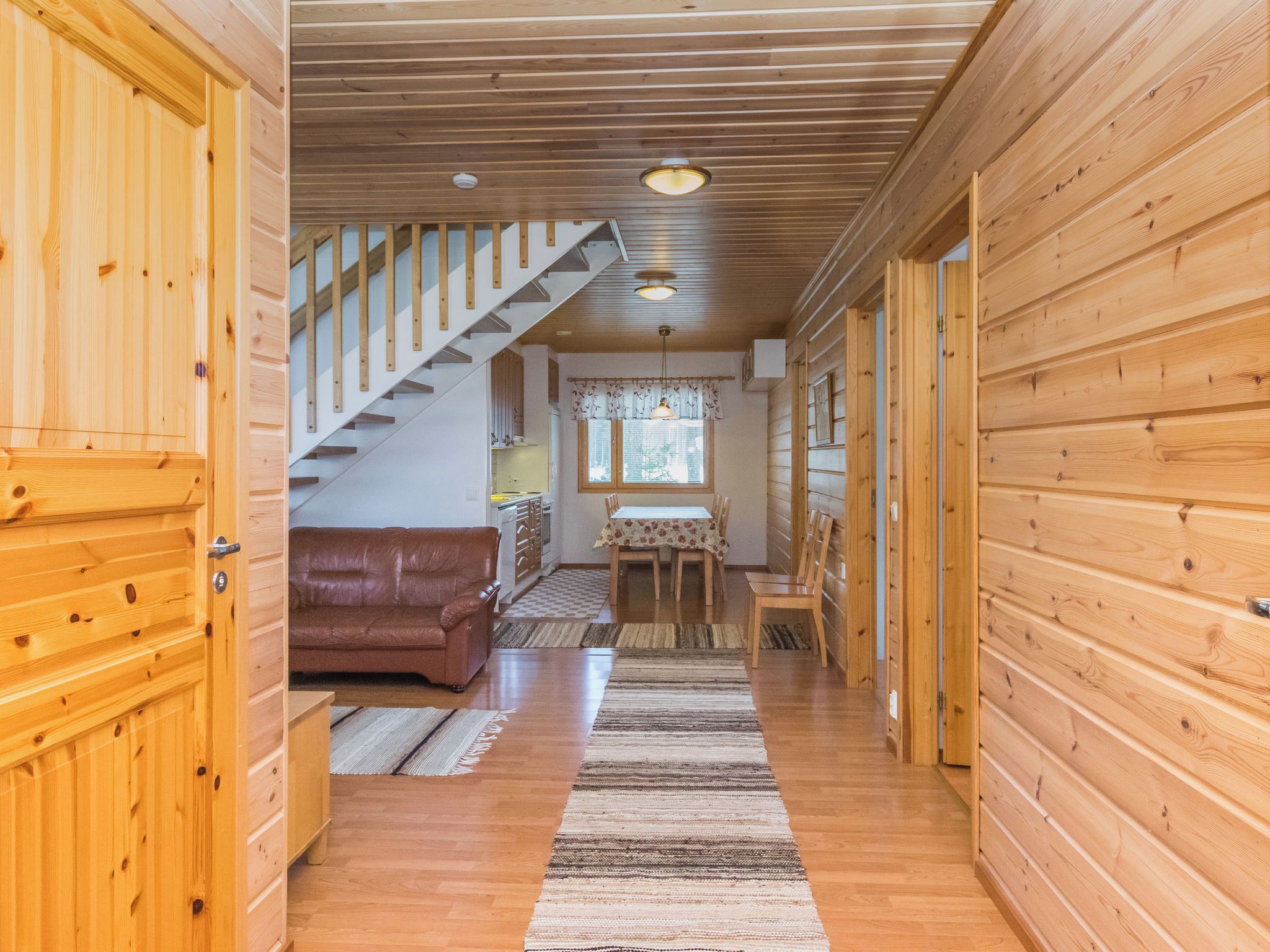 Un intérieur en bois comprenant un escalier, un coin repas et un salon avec un canapé.