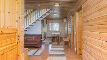 Et interiør i træ med en trappe, et spiseområde og en stue med en sofa.