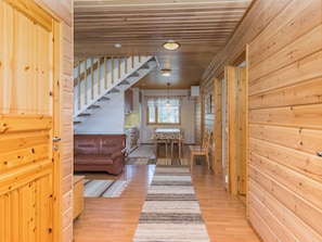 Un intérieur en bois comprenant un escalier, un coin repas et un salon avec un canapé.