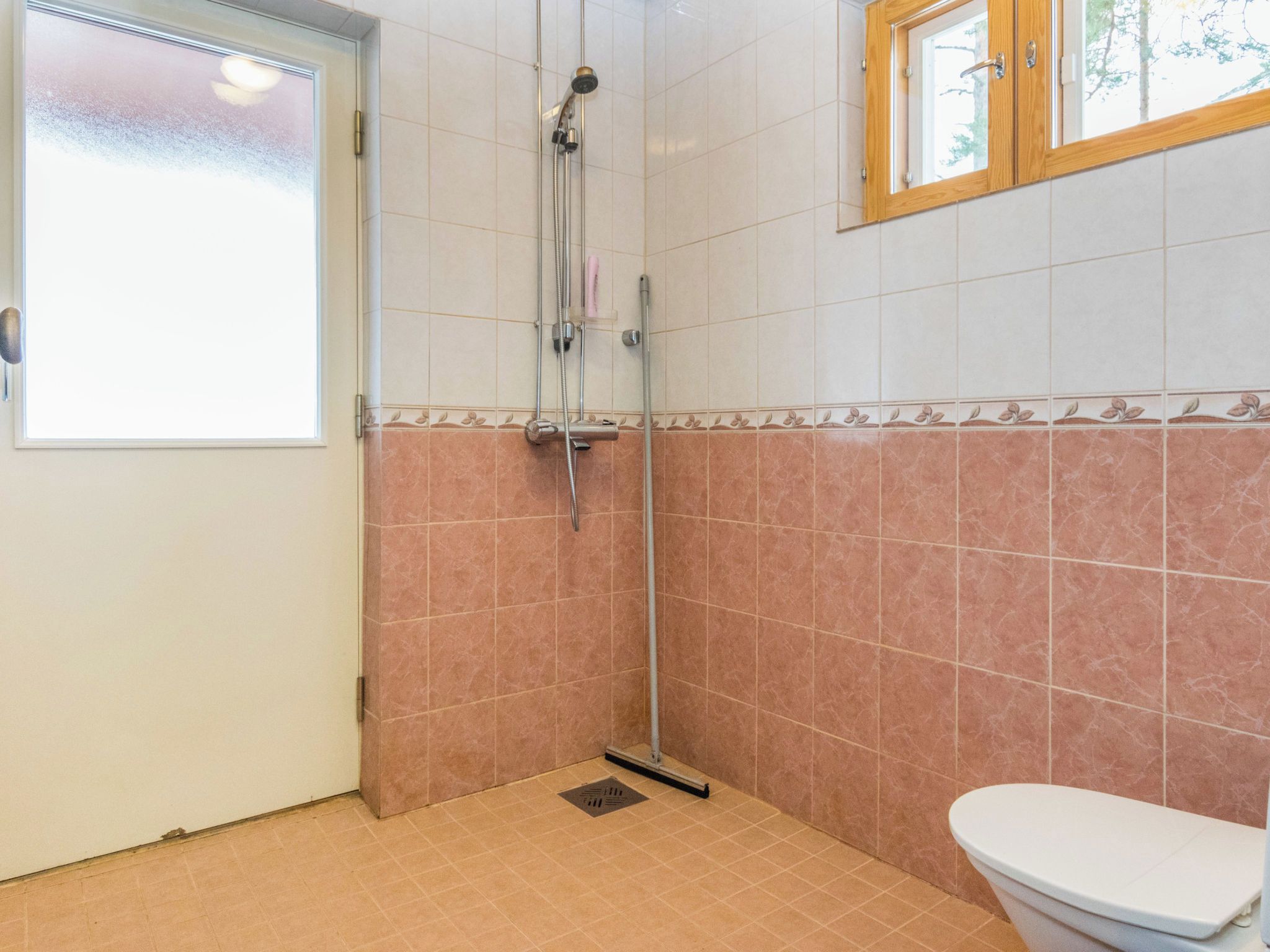Kylpyhuone, jossa on suihku, wc ja ikkuna.