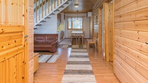 L’intérieur d’un chalet en bois comprend un escalier menant à une cuisine, un coin repas et un salon avec un canapé.