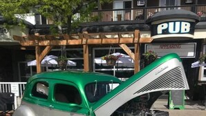 Un coche antiguo con el capó abierto, estacionado en una calle.