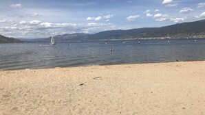 Una playa con cielo despejado, agua tranquila y montañas a lo lejos.