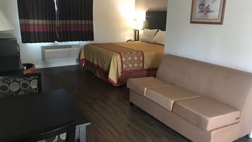 Una habitación de hotel con cama, sofá, escritorio y lámpara.