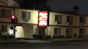 A motel with a red neon sign, multiple windows, and a visible street sign.