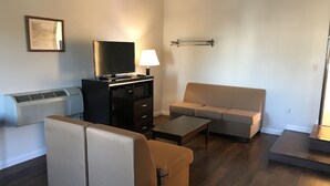 A living room with a sofa, a coffee table, a TV stand, and a wall-mounted lamp.