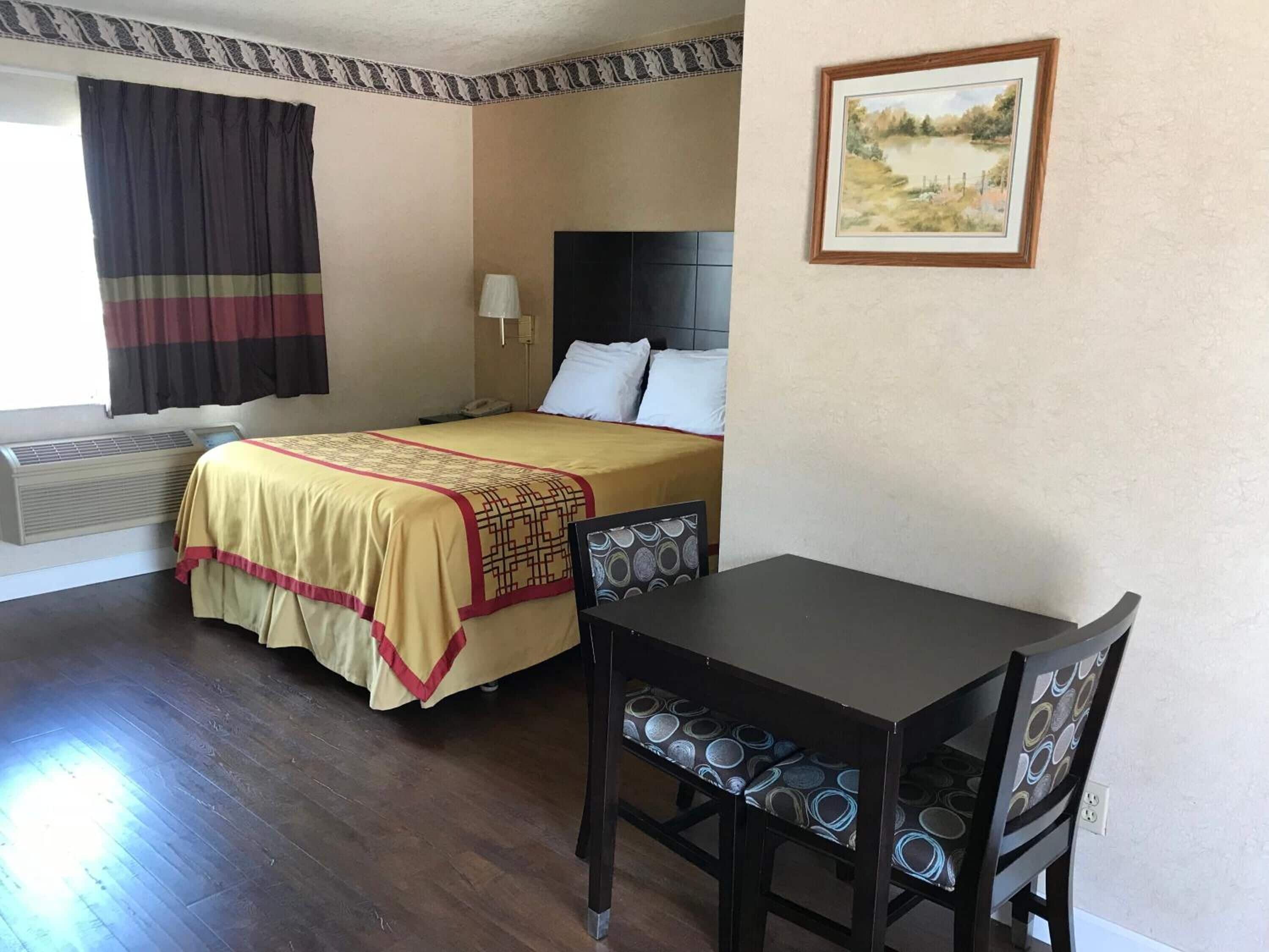 A hotel room with a bed, bedside table, and chair.