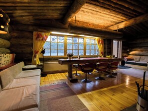 A cozy log cabin interior with a dining area, sofas, and a large window with curtains. - Veijon kelo by Interhome (Jyväskylä)
