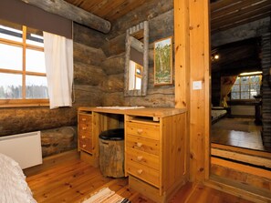 A log cabin room with a wooden dresser, a mirror, and a window with curtains. - Veijon kelo by Interhome (Jyväskylä)