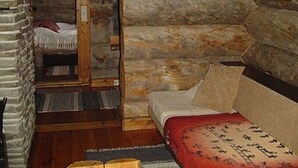 Ein Zimmer in einer Blockhütte mit einem Bett, einer Holzbank und einer Steinwand.