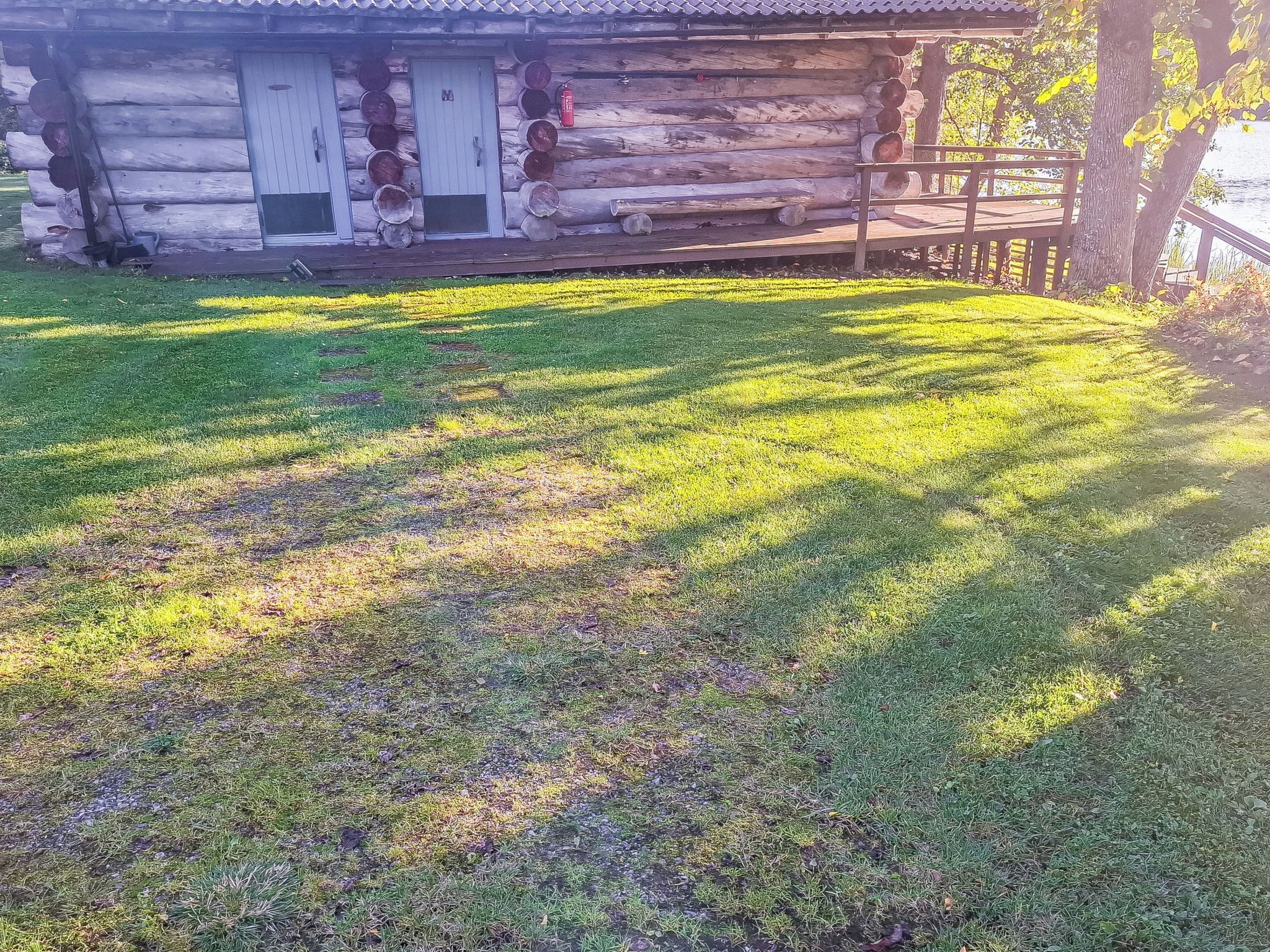 A log cabin with a wooden deck and a grassy yard.