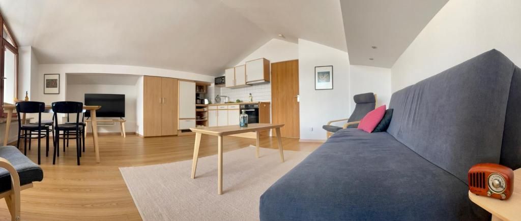 Ein modernes Wohnzimmer mit einer Couch, Sesseln, einem Couchtisch und einem Fernseher.
