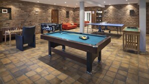 Een biljartkamer met een pooltafel, een tafelvoetbaltafel en een pingpongtafel.