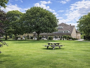 Ein großes Haus mit Rasen und einem Picknicktisch im Vordergrund.