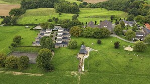 Luchtbeeld van een landelijk gebied met een groep huizen, omringd door velden en bomen.