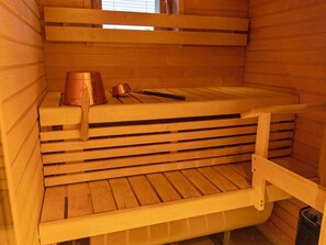 Una sauna con bancos de madera y un cubo de metal.