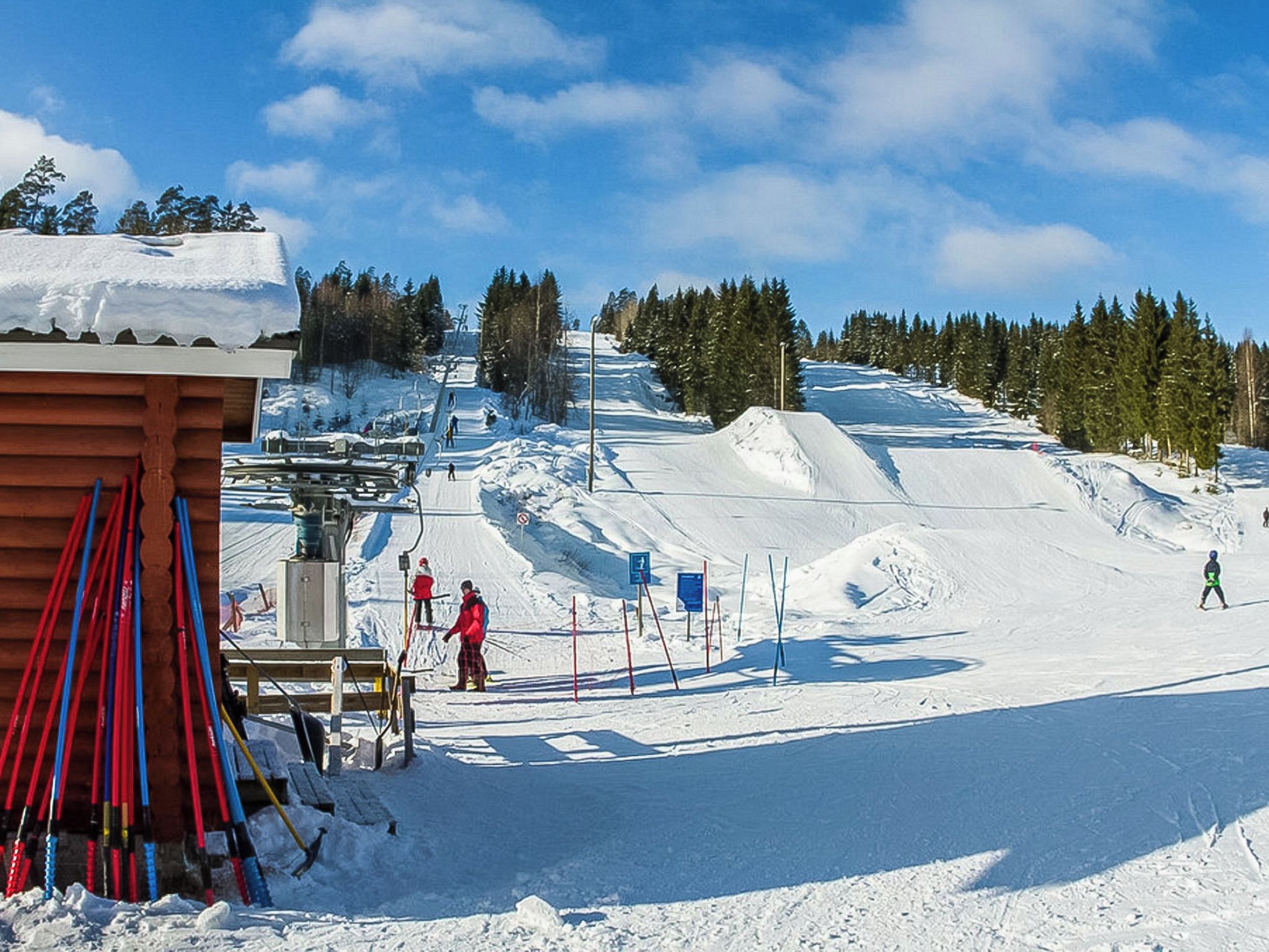 A ski resort with a ski lift, snow-covered slopes, and a wooden building.
