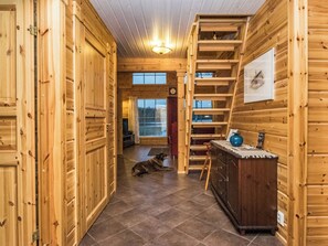 A wooden interior with a dog lying on the floor, a staircase, and a door with a window. - Myllymökki by Interhome (Hartola)