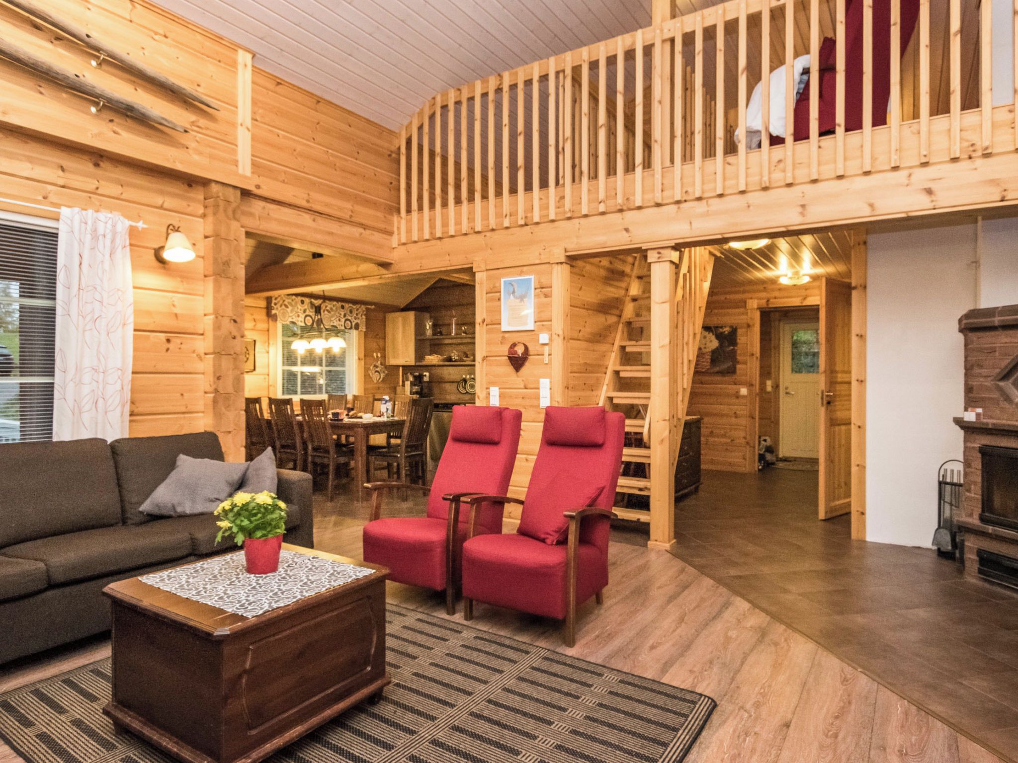 Ein Holzinterieur mit Balkon, einer Couch, einem Couchtisch und einem Kamin.