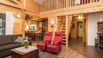 Ein Holzinterieur mit Balkon, einer Couch, einem Couchtisch und einem Kamin.