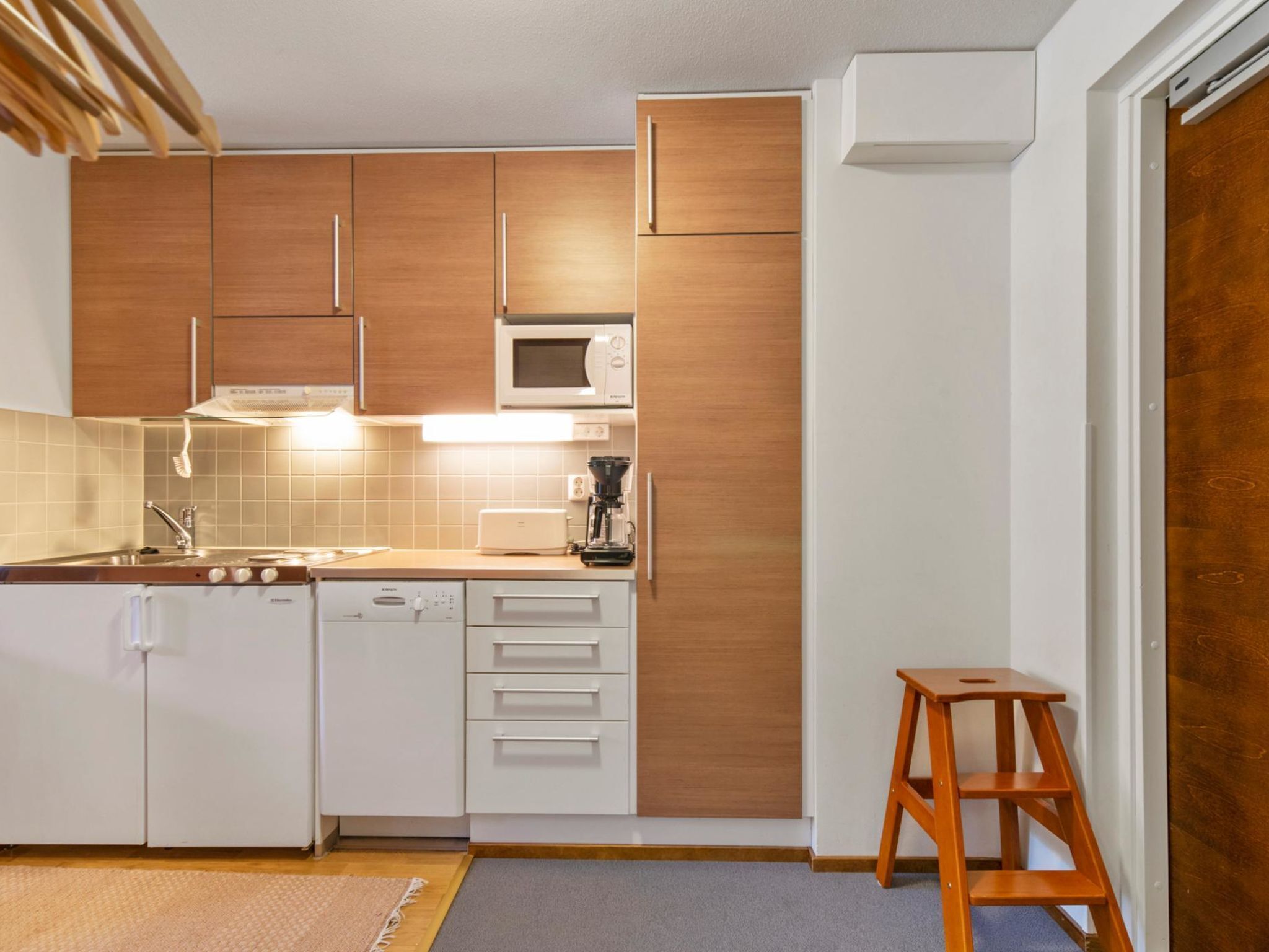 A compact kitchen with wooden cabinets, a microwave, a dishwasher, and a coffee maker.