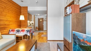 Un salon moderne avec des lambris en bois, un coin repas et une cuisine.