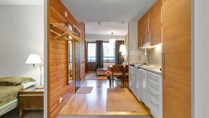 Une pièce de taille modeste comprenant un lit, un bureau, une chaise, une table à manger et un coin cuisine.