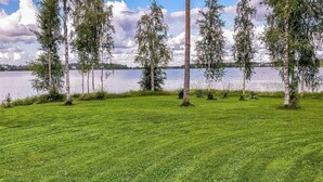 Un campo cubierto de hierba con árboles y una masa de agua al fondo.