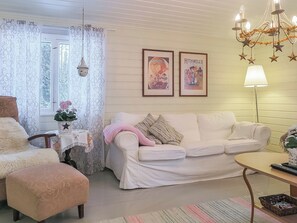A cozy living room with a white sofa, a small table, a chair, and a lamp. There are two framed pictures on the wall. - Inninniemi by Interhome (Pyhäjärvi)
