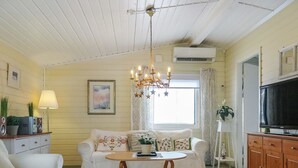Una sala de estar acogedora con un sofá blanco, una mesa de centro de madera, un televisor y una araña.