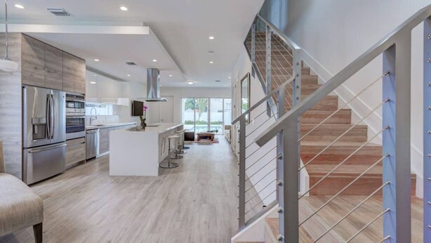 A modern kitchen with stainless steel appliances, a central island, and a staircase with metal railings. -  Poolside Sanctuary 4B 4B heated pool ,Jacuzzi 1Gb internet.  (Miami)