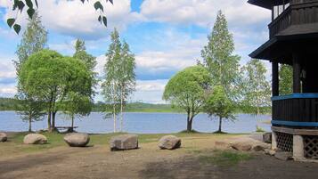 Näkymä järvelle, jossa on puinen mökki, suuria kiviä ja puita.