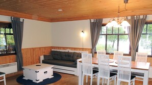 A cozy room with a wooden ceiling, a sofa, a dining table with chairs, and a window with curtains. - Kiviniemi by Interhome (Tohmajärvi)